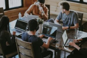 Gruppe von Leuten sitzt am Tisch und nutzt laptops